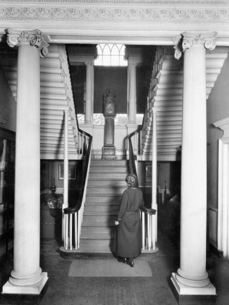 Woman Stands at the Foot of a Colonial Staircase